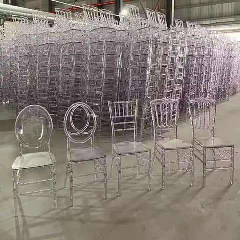 Five clear acrylic chairs in a warehouse