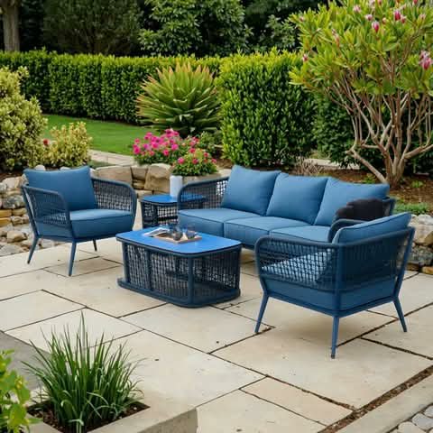A blue outdoor sofa set with table, on a garden patio.