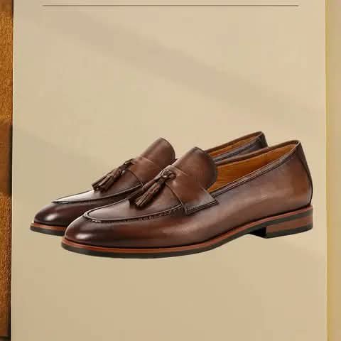 Brown leather tassel loafers on a beige background.