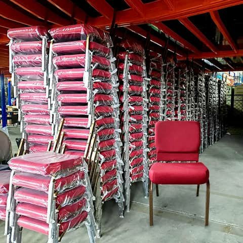 Stacks of red church chairs in a warehouse