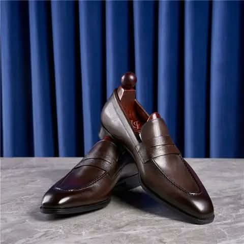 Dark brown loafers, one raised on a shoe tree.