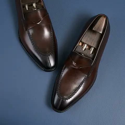 Dark brown penny loafers seen from above, with shoe trees.