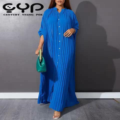 A woman wearing a long royal-blue pleated shirt-style dress, holding a green handbag.