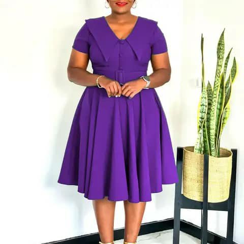 A woman wearing a purple fit-and-flare dress with short sleeves.