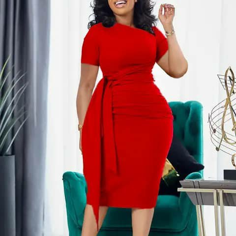 A woman wearing a red short-sleeve fitted dress with a waist tie, indoors.