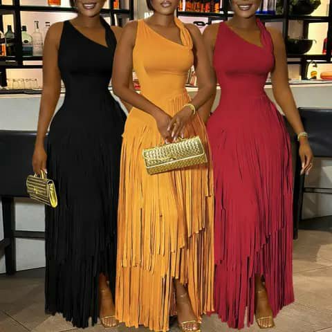 Three women wearing long one-shoulder fringed dresses in black, orange and red, holding clutches.