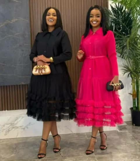 Two women wearing shirt dresses with ruffled hems in black and hot pink, holding clutches.