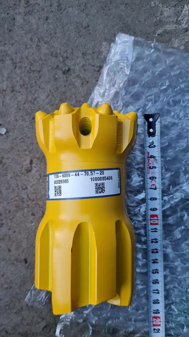 A single yellow drill bit with a label, shown next to a tape measure.