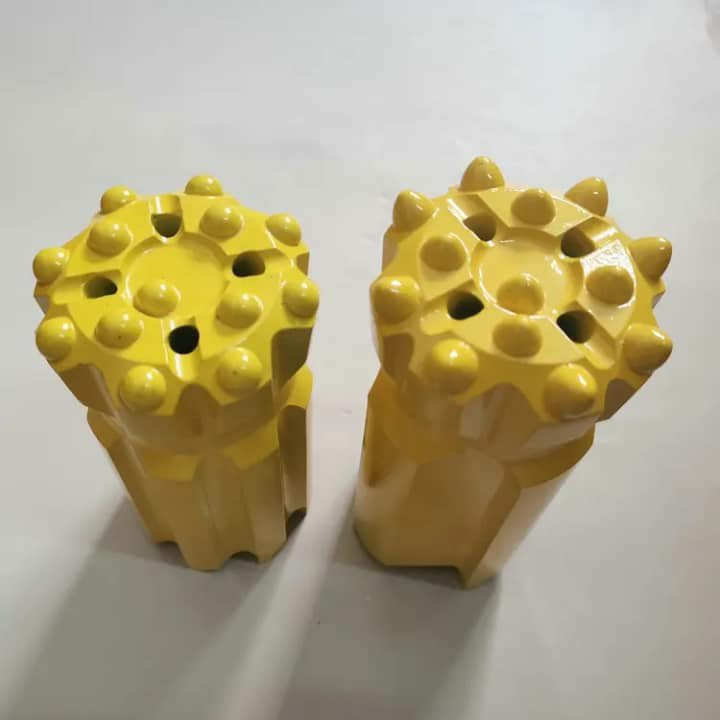 Two yellow button-type drill bits with rounded studs on the face.