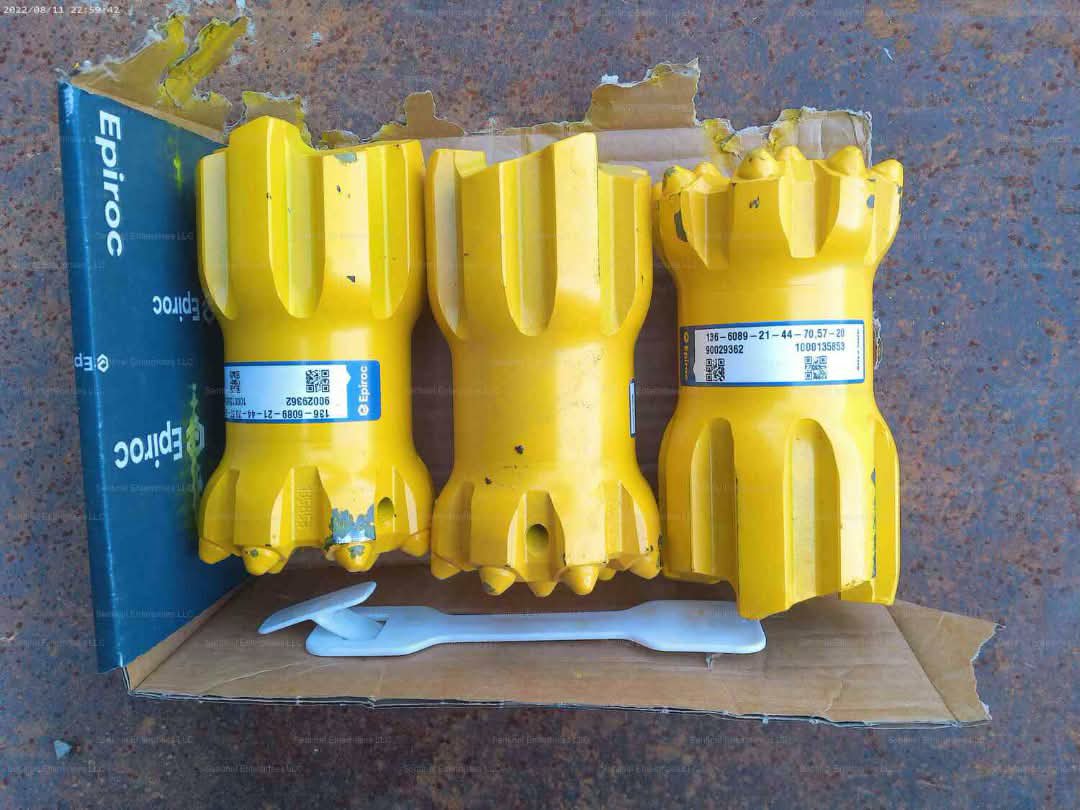 Three yellow drill bits with labels standing in an open box.