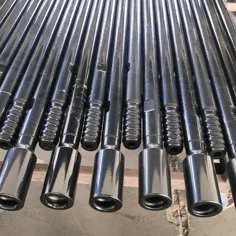 A close-up row of black drill rods with threaded ends.