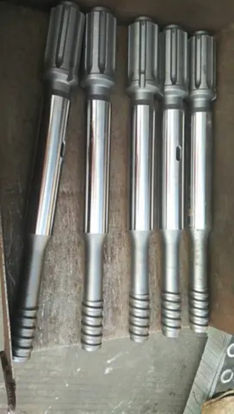 Five silver drill rods standing upright in a box.