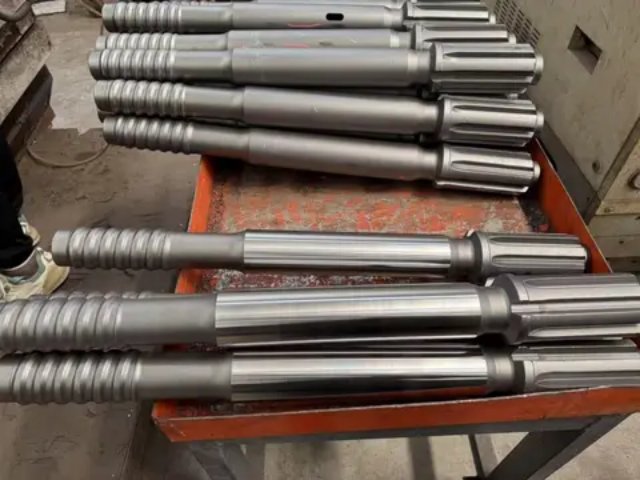 Silver drill rods stacked on a red cart.