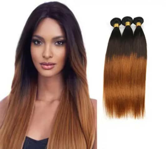 A woman wearing long straight ombré hair, dark at the roots fading to copper, beside three bundles of the same hair.