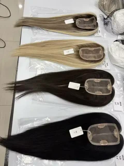 Four hair toppers laid out, blonde brown and black