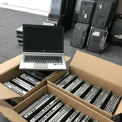 HP laptop open in front of cartons full of laptops