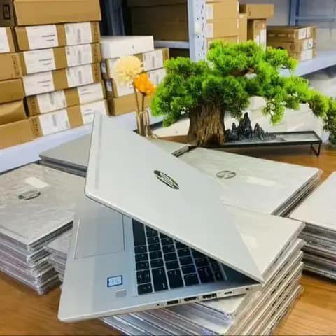 Stack of silver HP laptops, one open in front