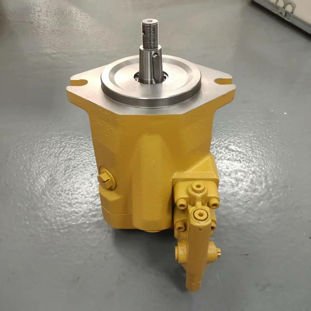 A yellow hydraulic pump with a silver top and shaft pointing up, on a grey floor.