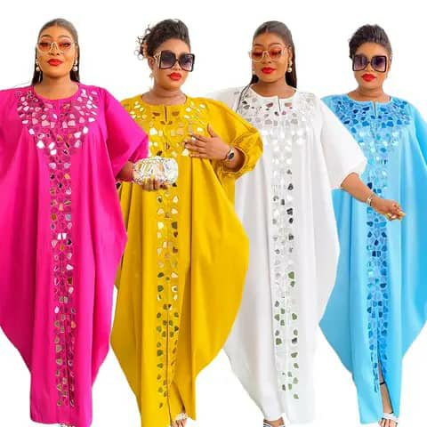 Four women wearing long embellished kaftans in pink, yellow, white and light blue.