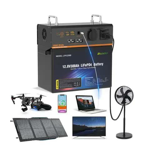 LiFePO4 battery 12.8V 300Ah shown with solar panels, fan, laptop and TV