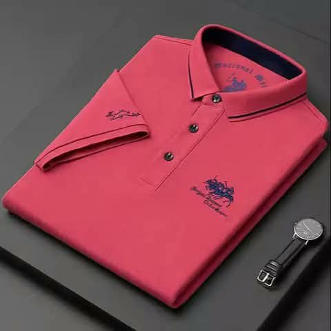 A pink polo shirt beside a watch.