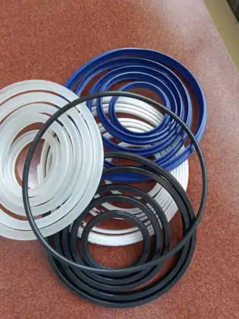 Coils of seal rings in white, blue and black on a brown surface.