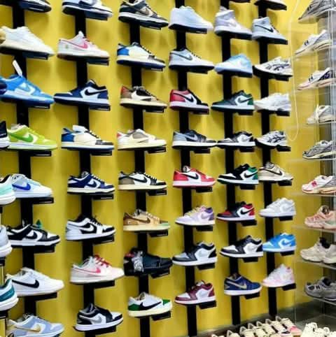 Sneakers displayed in rows on a yellow wall.