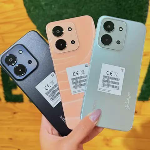 Three Tecno smartphones held up, in black, peach and mint